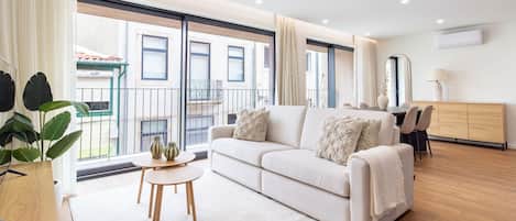 A modern living room with a sofa, a round table, and a view of the outside.