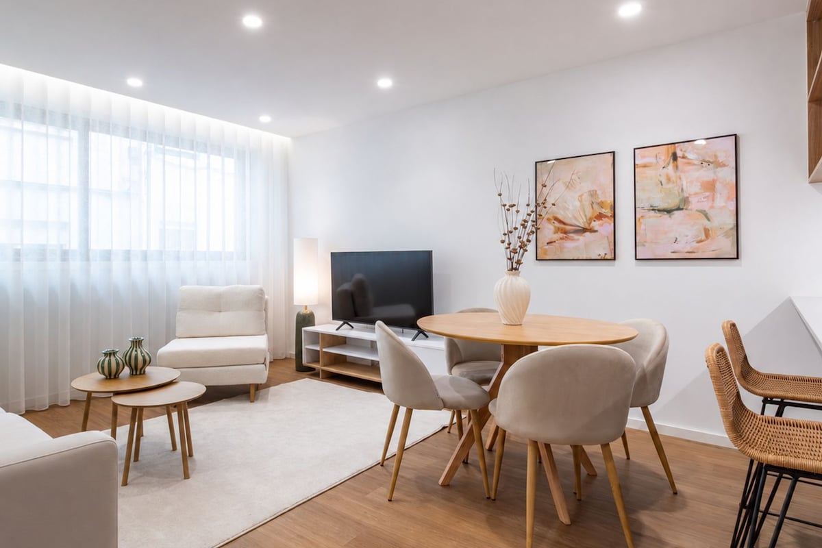 Una sala moderna con sofá, mesa de centro, televisión y comedor.