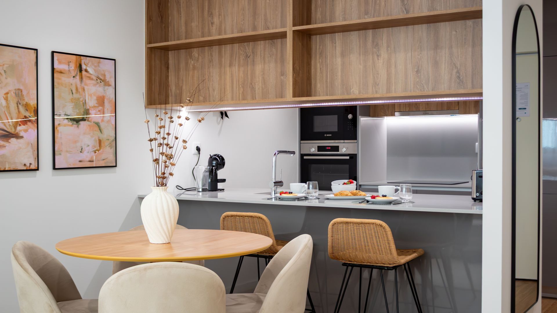 Una cucina moderna con isola centrale, mobili in legno e zona pranzo con sedie in vimini.