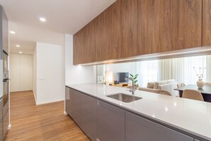 Una cocina moderna con un armario superior de madera, un lavamanos de acero inoxidable y una encimera elegante.