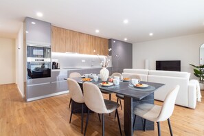 A modern kitchen with built-in appliances, a dining area with a marble table, and a living room with a white sofa. - Polacos Residence by LovelyStay (Vila Nova de Gaia)