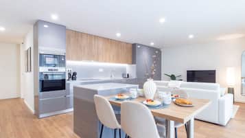 Una cocina moderna con una isla central, electrodomésticos integrados y un comedor con una mesa lista para el desayuno.