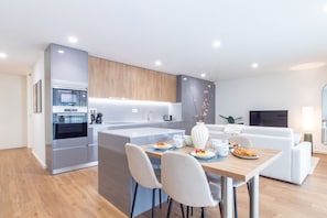 Una cocina moderna con una isla central, electrodomésticos integrados y un comedor con una mesa lista para el desayuno.