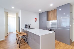 Una cocina moderna con una isla central, taburetes de bar, horno empotrado y refrigerador.
