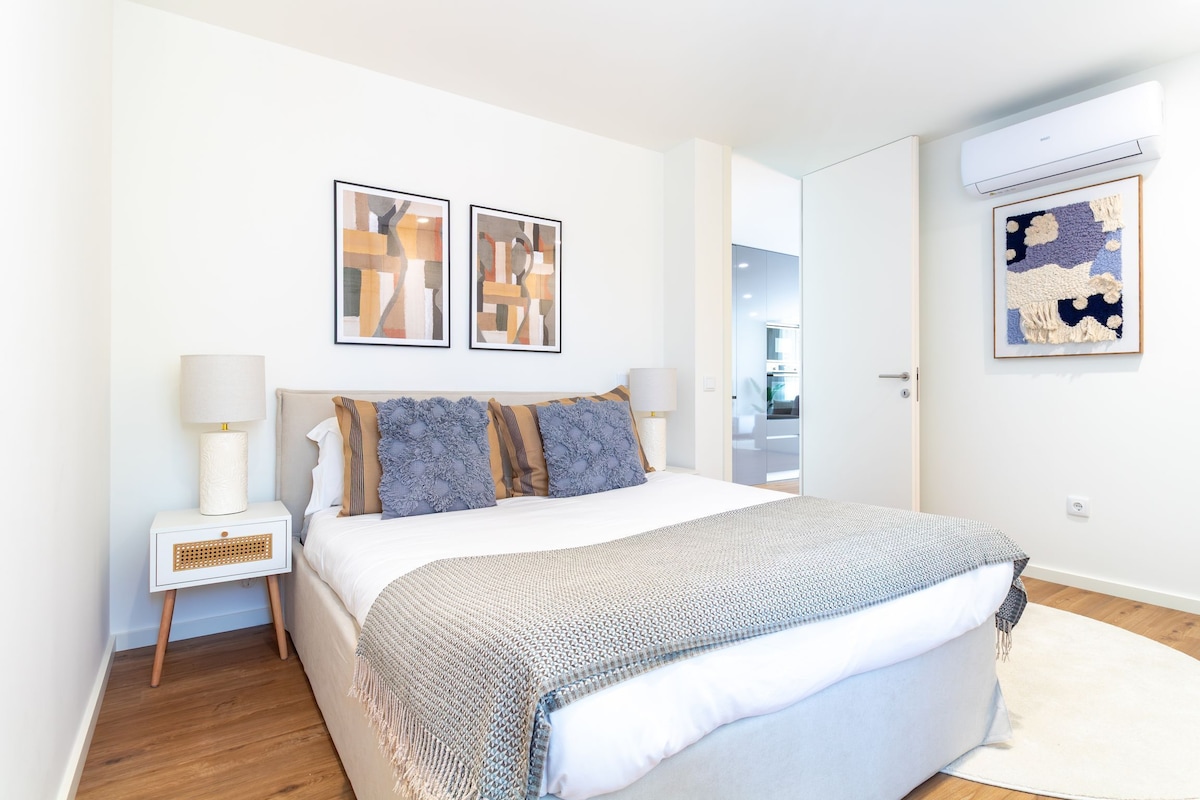 A modern bedroom with a large bed, two bedside tables, and artwork on the walls.