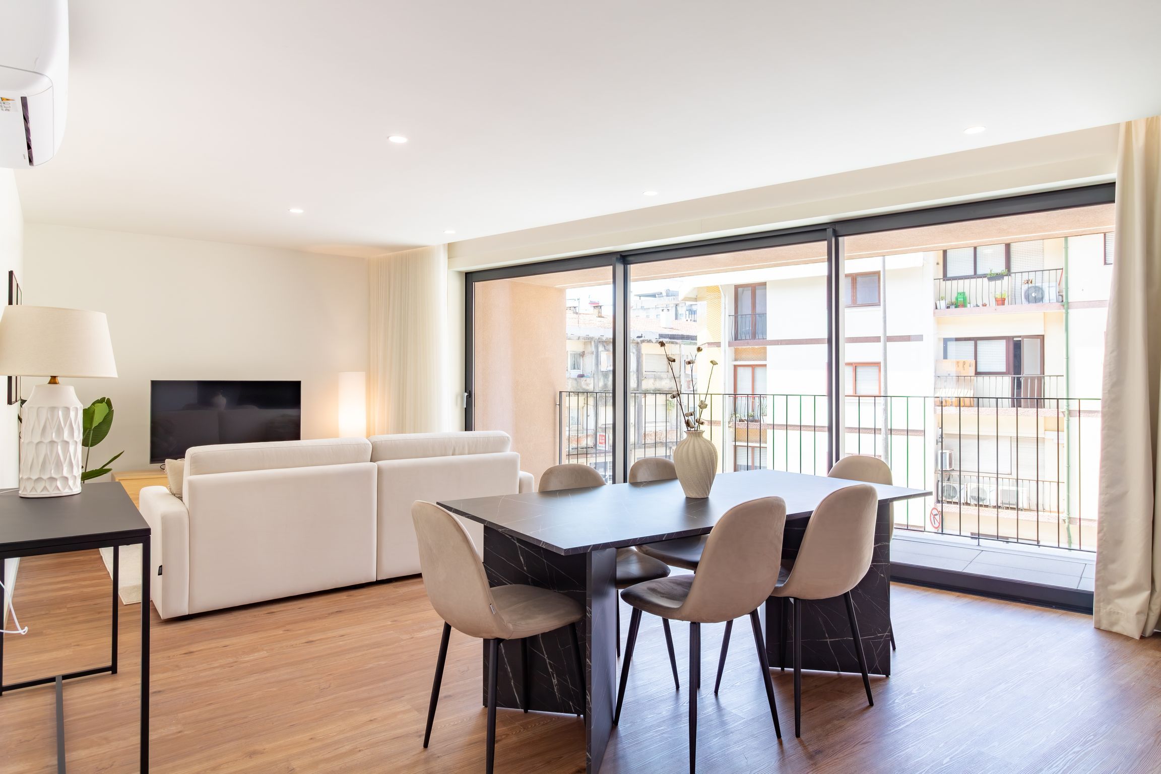 A modern living room with a sofa, TV, and dining area with chairs and a table.
