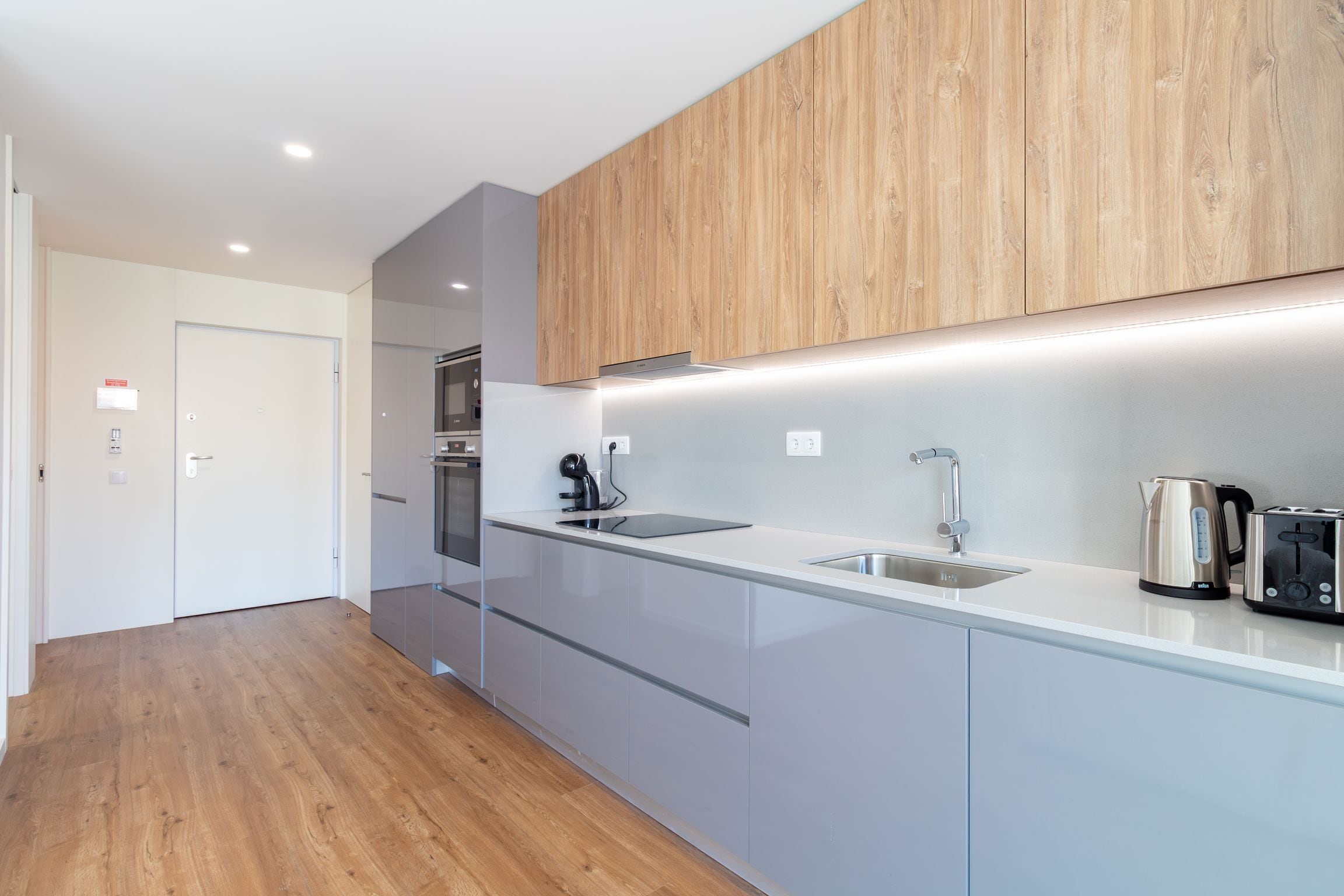 A modern kitchen with a stainless steel sink, a kettle, and a toaster.