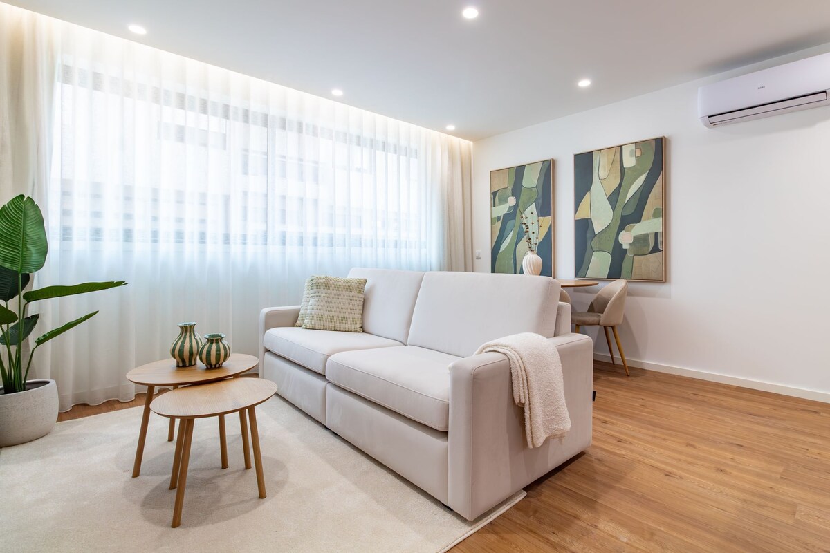 A modern living room with a sofa, a small round table, and a potted plant.