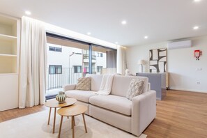 Un salón moderno con un sofá, una mesa redonda pequeña y vistas al exterior.