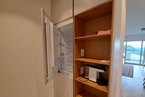 A kitchen with a built-in microwave, a wooden shelf with kitchenware, and a view of the outdoors. - Apartment with 1 bedroom (Annenheim am Ossiachersee)
