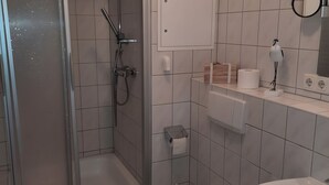 Un bany modern amb dutxa, vàter i rentapeus.