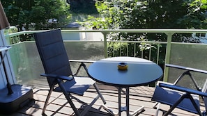 Eine Terrassengruppe im Freien mit einem runden Tisch und zwei Stühlen, umgeben von einem Metallzaun.