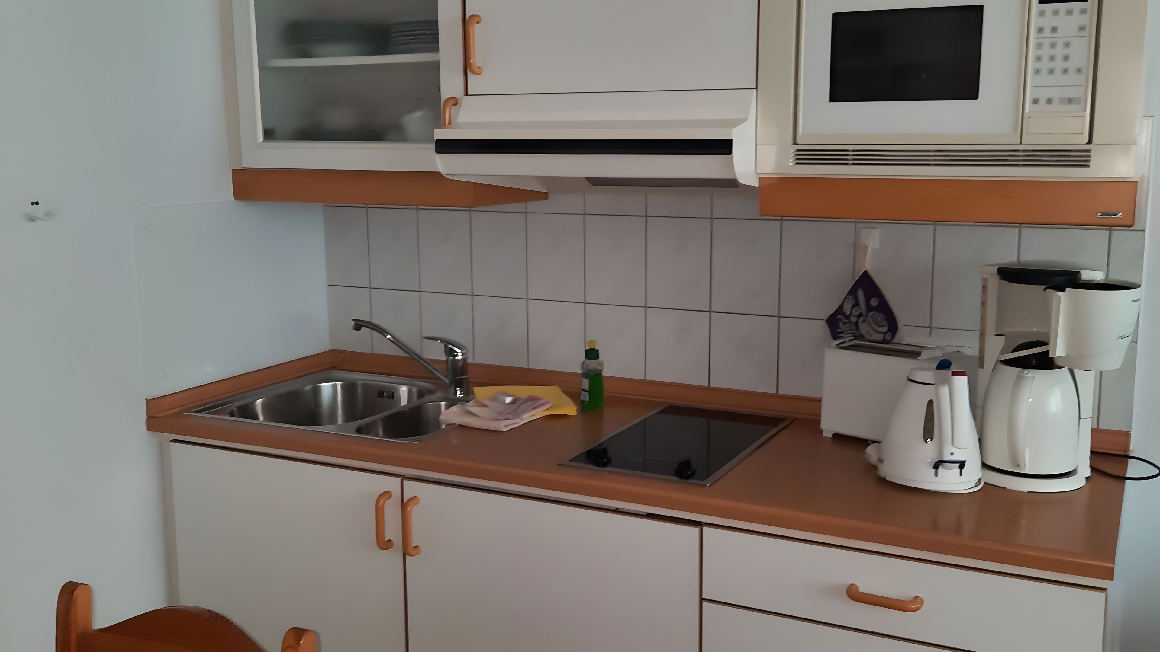 Eine Küche mit Spüle, Mikrowelle, Kaffeemaschine und Schränken.