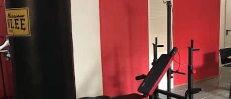 Ein Fitnessstudio mit einem Schlagbeutel, einer Hantelbank und Gewichthebergeräten.