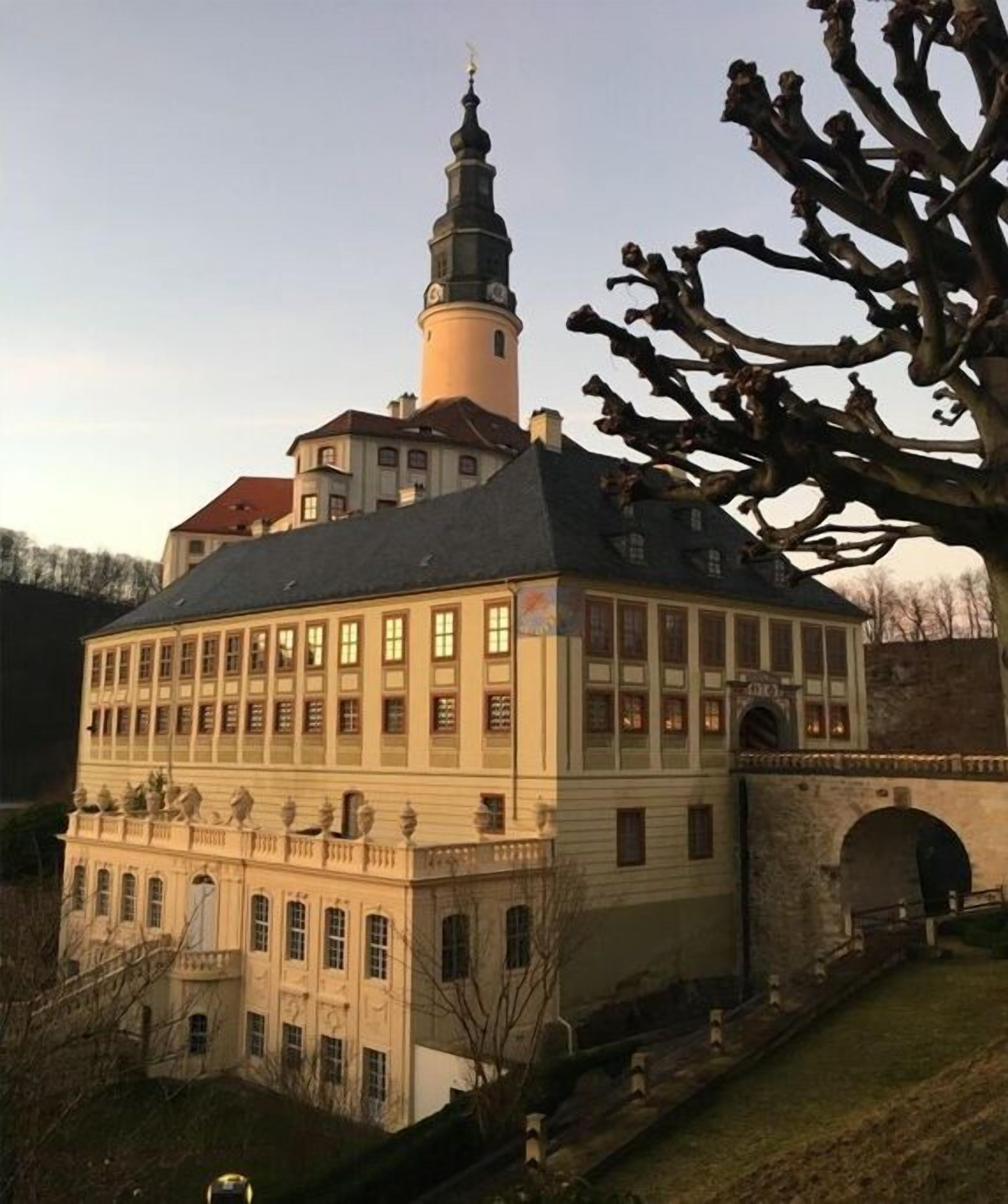 A historic building with a prominent tower and a large central section with multiple windows.