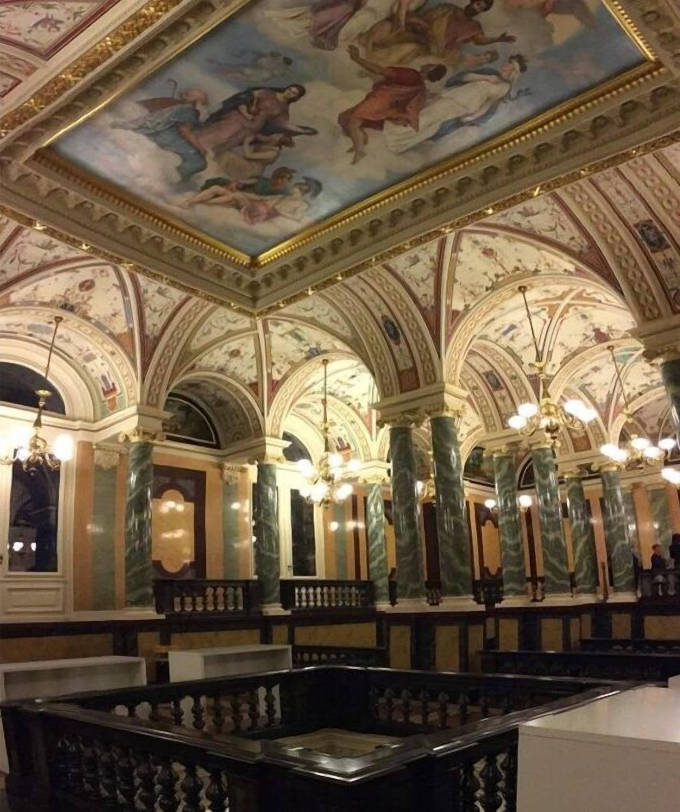 Ein Innenraum mit gewölbten Decken, Marmorsäulen und einem Chandelier.