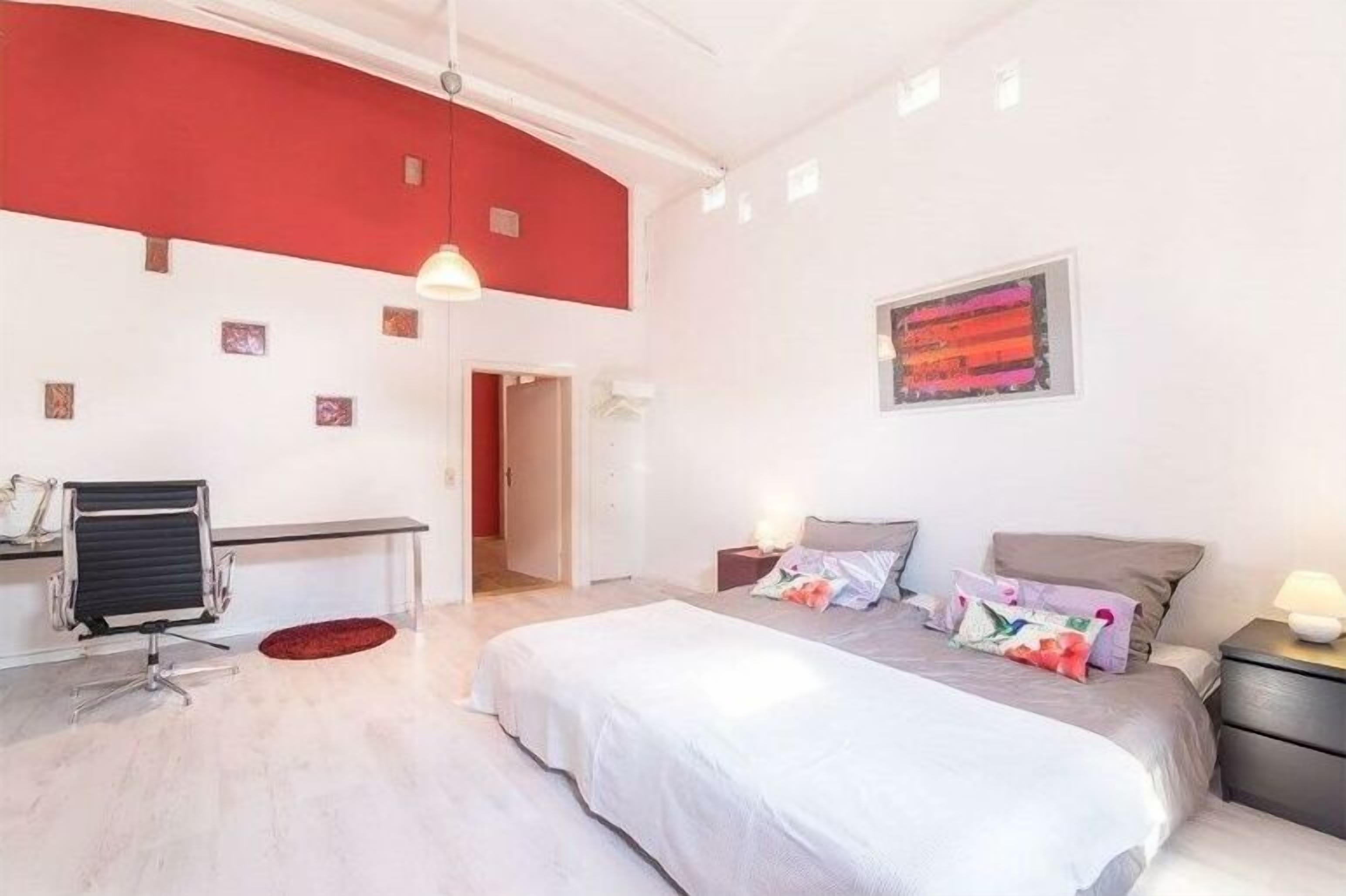 Une chambre à coucher avec un lit, des tables de chevet, un bureau et une chaise.