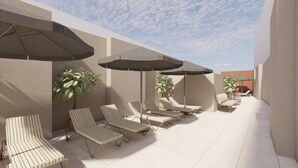 A sunlit outdoor seating area with lounge chairs and umbrellas, surrounded by walls and potted plants.