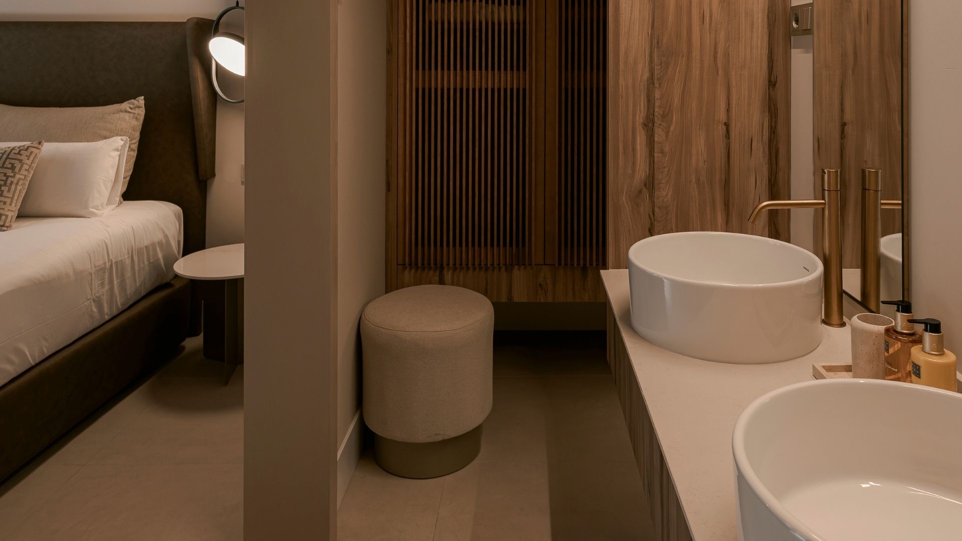 A modern bathroom with a large bathtub, a round sink, and a toilet.