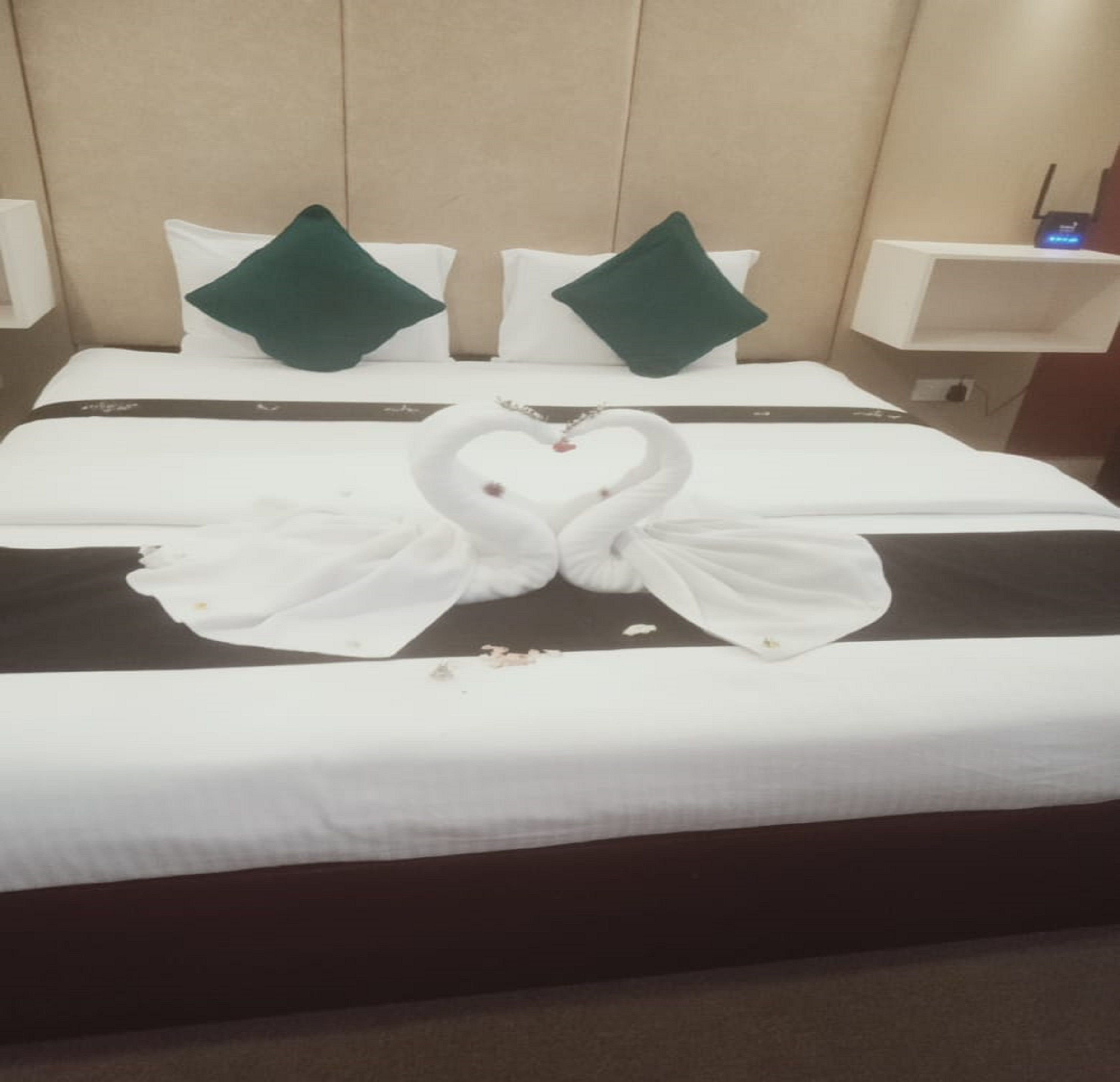 Une chambre d’hôtel avec un lit, des oreillers et une décoration en forme de cygne réalisée avec des serviettes.