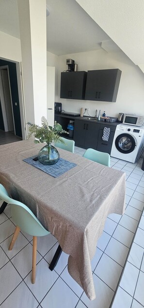 Ein Essbereich mit Tisch, Stühlen und einem Blumenstrauß.