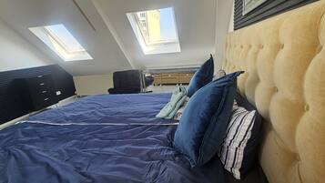 Ein Schlafzimmer mit einem großen Bett, zwei Fenstern, einem schwarzen Kleiderschrank und einer Kopfteil.