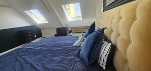 Ein Schlafzimmer mit einem großen Bett, zwei Fenstern, einem schwarzen Kleiderschrank und einer Kopfteil.