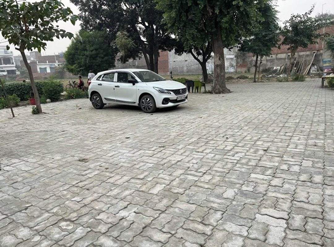 Un espacio exterior pavimentado con un coche blanco estacionado.