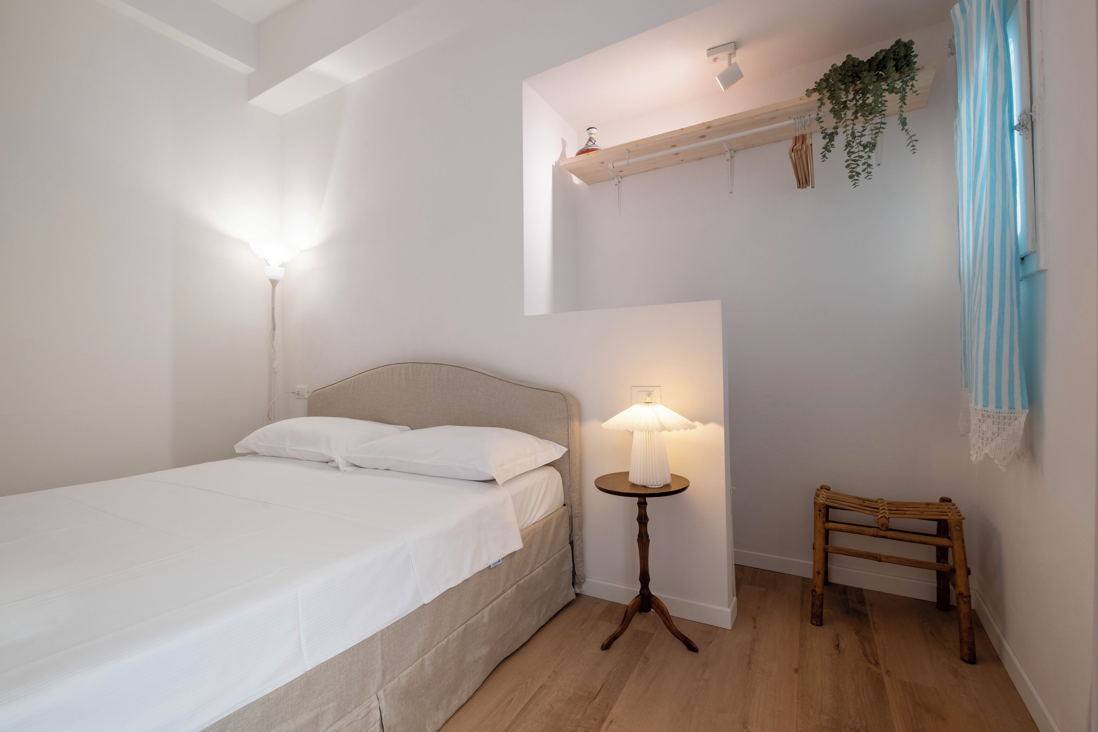Ein Schlafzimmer mit einem Bett, einem Nachttisch, einer Lampe und einem Sessel.