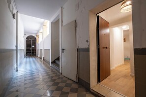 A corridor with a checkered floor leading to a door with a wooden finish. - La Sera dei Miracoli by Wonderful Italy (Bologna)