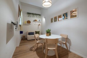 A dining area with a round table and four wooden chairs, a hanging light fixture, and wall-mounted shelves with decorative items. - La Sera dei Miracoli by Wonderful Italy (Bologna)
