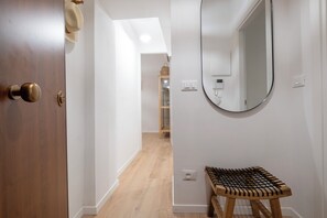 A hallway with a wooden door, a small stool, a mirror, and a shelf with items. - La Sera dei Miracoli by Wonderful Italy (Bologna)