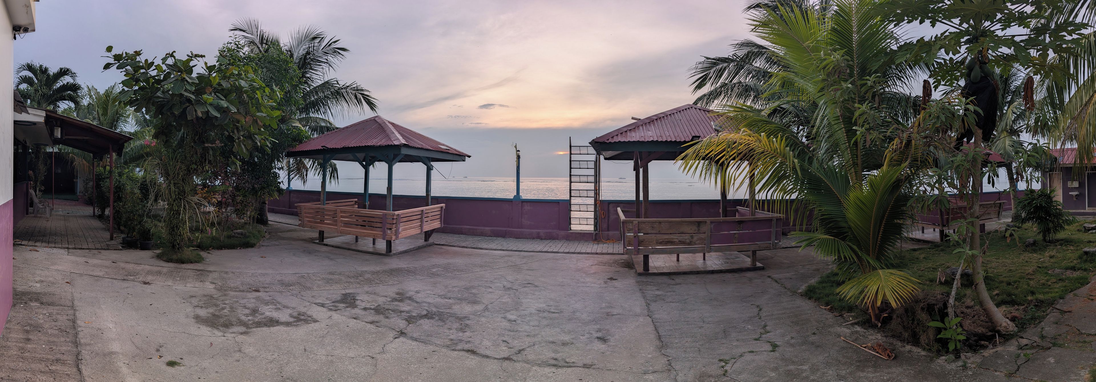 A seaside walkway with benches and gazebos, overlooking the ocean.