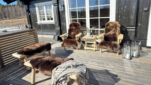 A wooden deck with outdoor furniture, including chairs and a bench, and a table with a glass top.