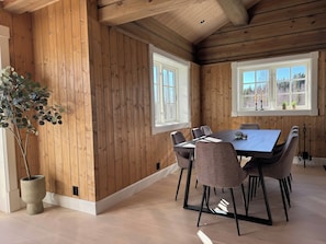 A dining area with a wooden interior, a large table, and chairs.