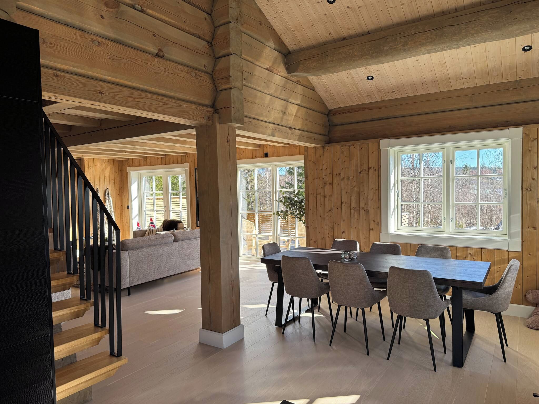 A spacious interior with a dining area, a staircase, and large windows.