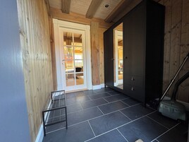 Un pasillo con una puerta que da a una habitación, un perchero metálico y una aspiradora.