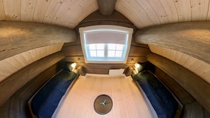A cozy attic room with a sloped ceiling, a skylight, two benches, and a central clock. - Familycabin at a Lake (Ringsaker)