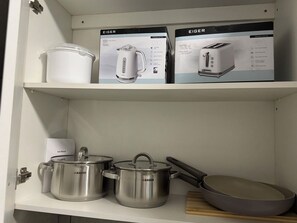Una estantería de cocina con una tetera, ollas y un tostador.