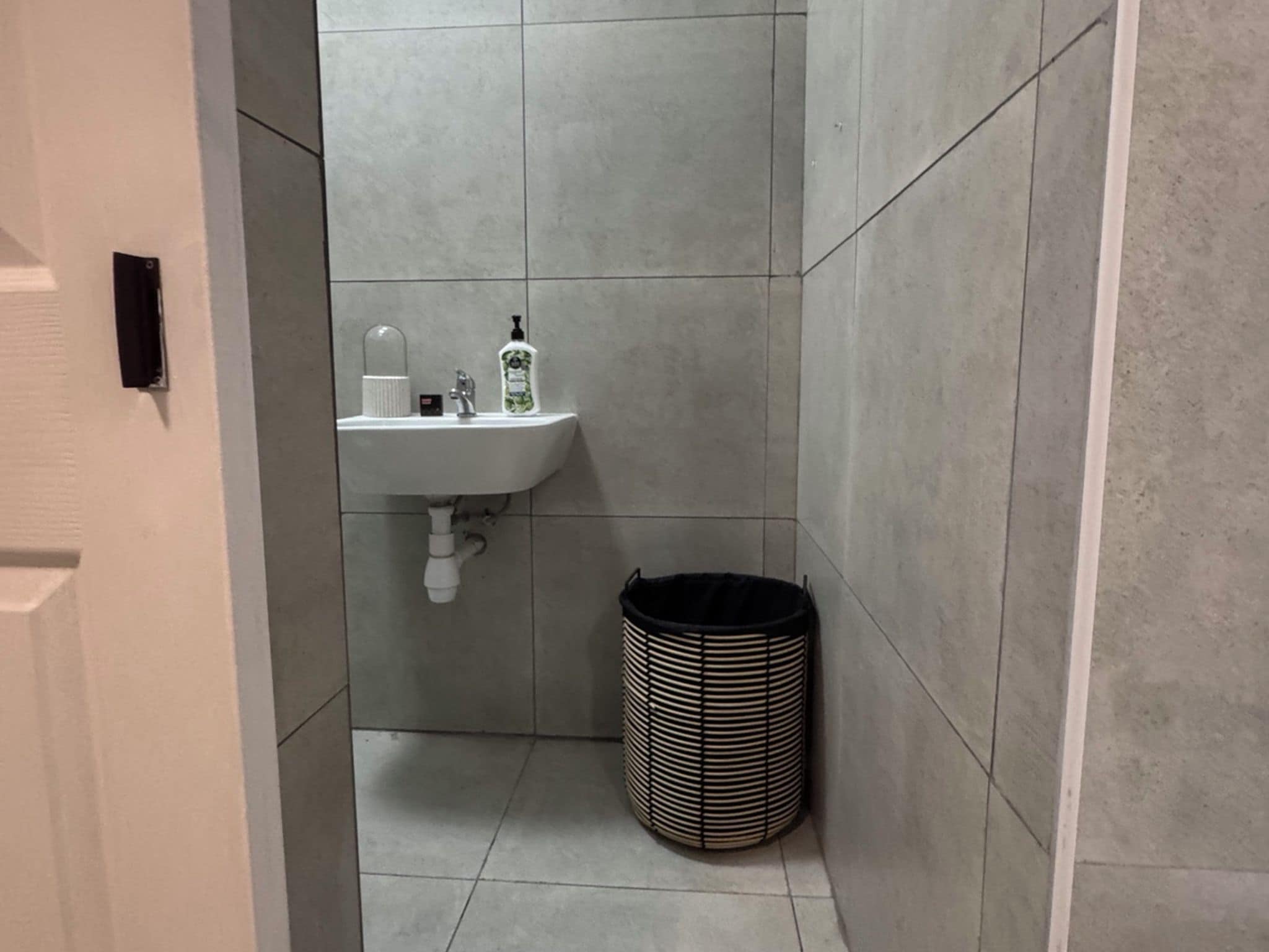 Un baño con lavamanos, un bote de basura y un inodoro.