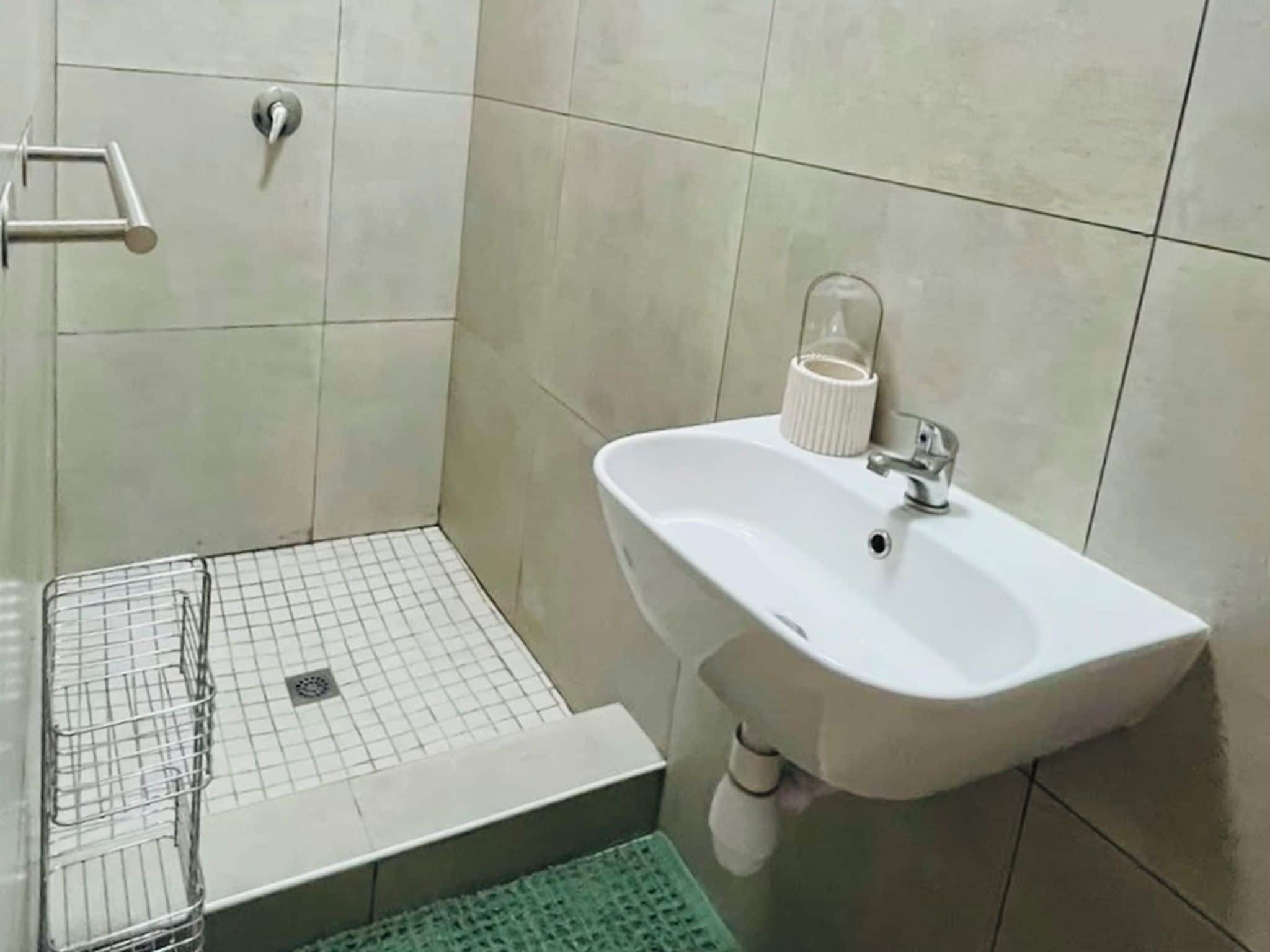 Un baño con lavamanos blanco, toallero y zona de ducha.