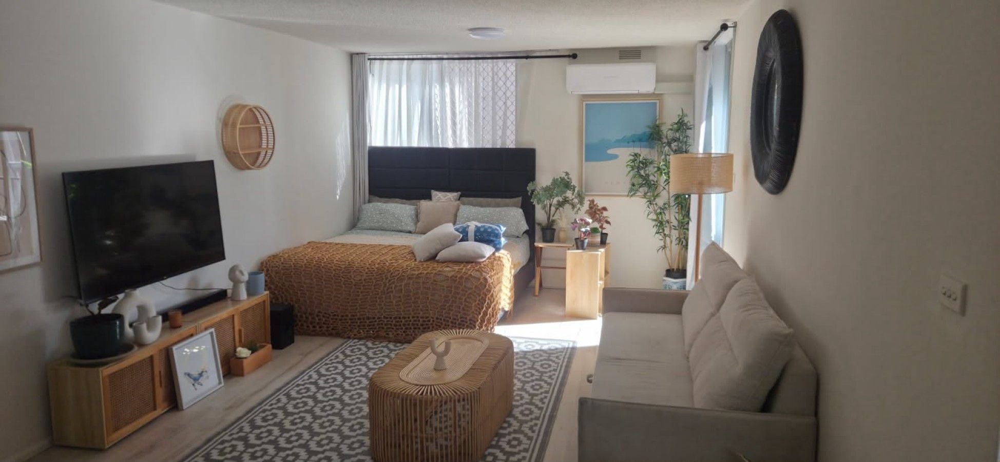 A bedroom with a bed, bedside table, lamp, and a television.