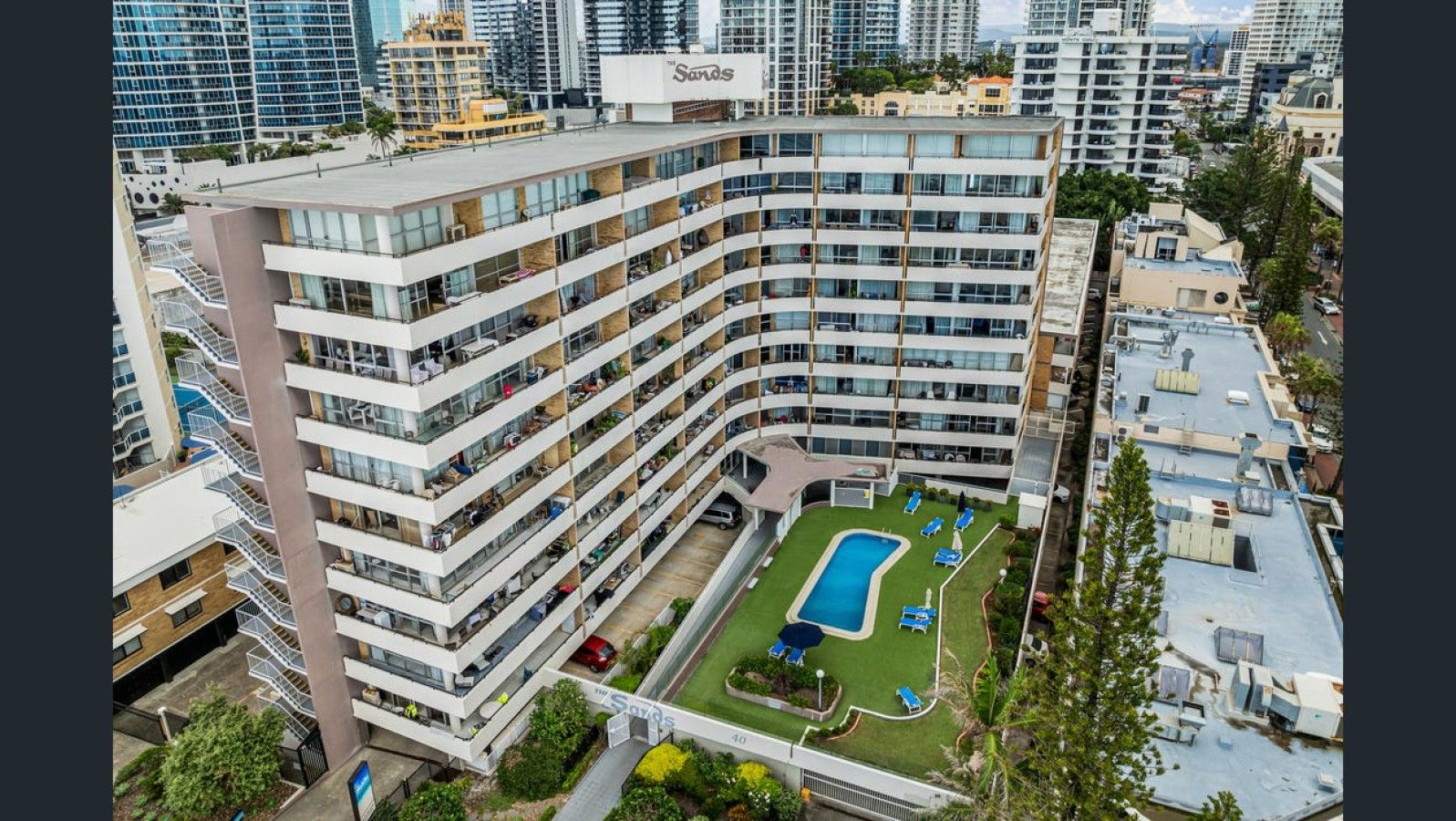 A high-rise hotel with multiple balconies, a rooftop pool, and a landscaped courtyard.