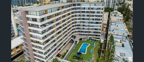 A high-rise hotel with multiple balconies, a rooftop pool, and a landscaped courtyard.