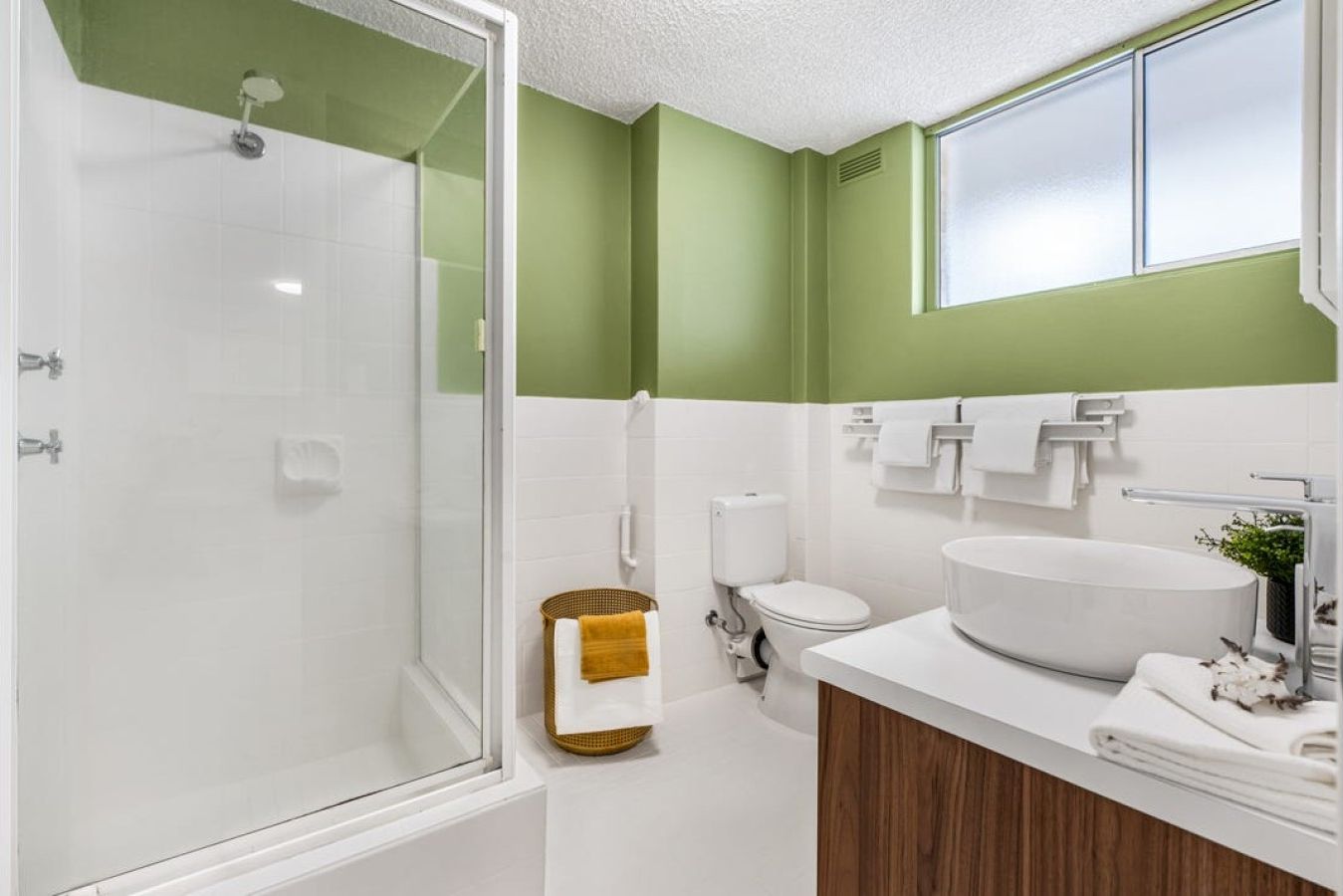 A modern bathroom with a glass shower enclosure, a white sink, and a toilet.