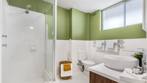 Ein modernes Badezimmer mit Duschkabine aus Glas, Waschbecken in Weiß und Toilette.