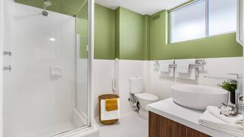 A modern bathroom with a glass shower enclosure, a white sink, and a toilet.