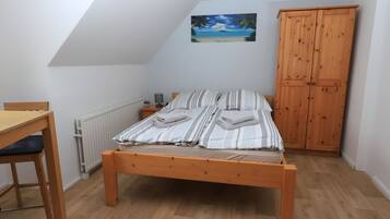 Ein Schlafzimmer mit einem Holzbett, einem Schreibtisch und einem Kleiderschrank.