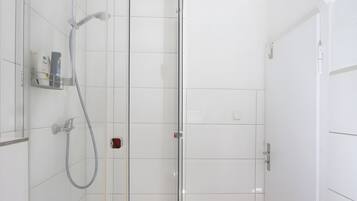 Ein modernes Badezimmer mit Duschkabine aus Glas, einer Handbrause und einem wandmontierten Wasserhahn.
