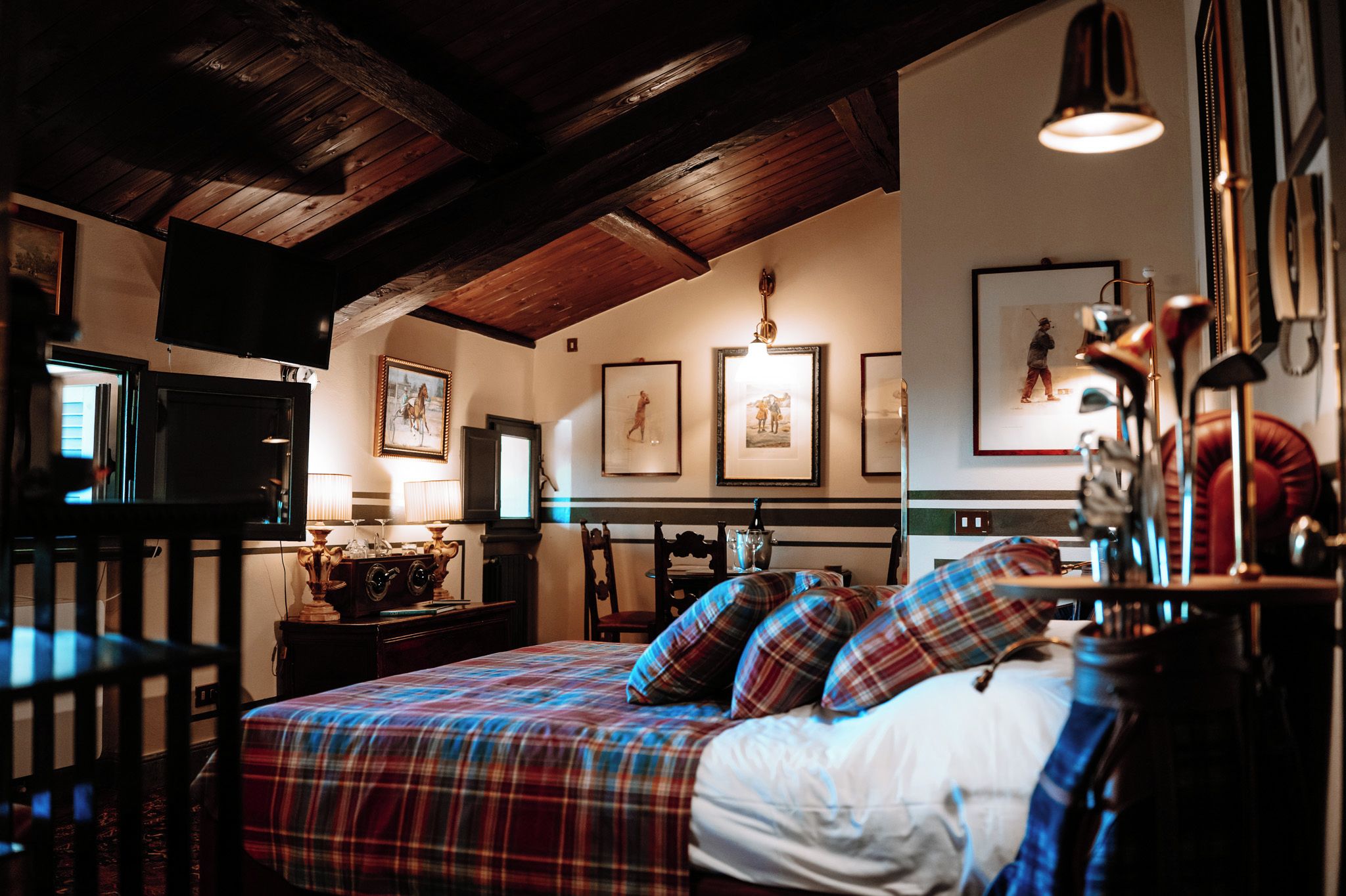 Een kamer met een bed, bureau, televisie en ingelijste foto's aan de muur.
